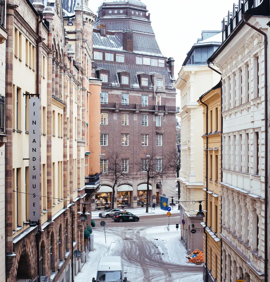 Snöig gata i Stockholms innerstad med butiker i gatuplan och stenfasader