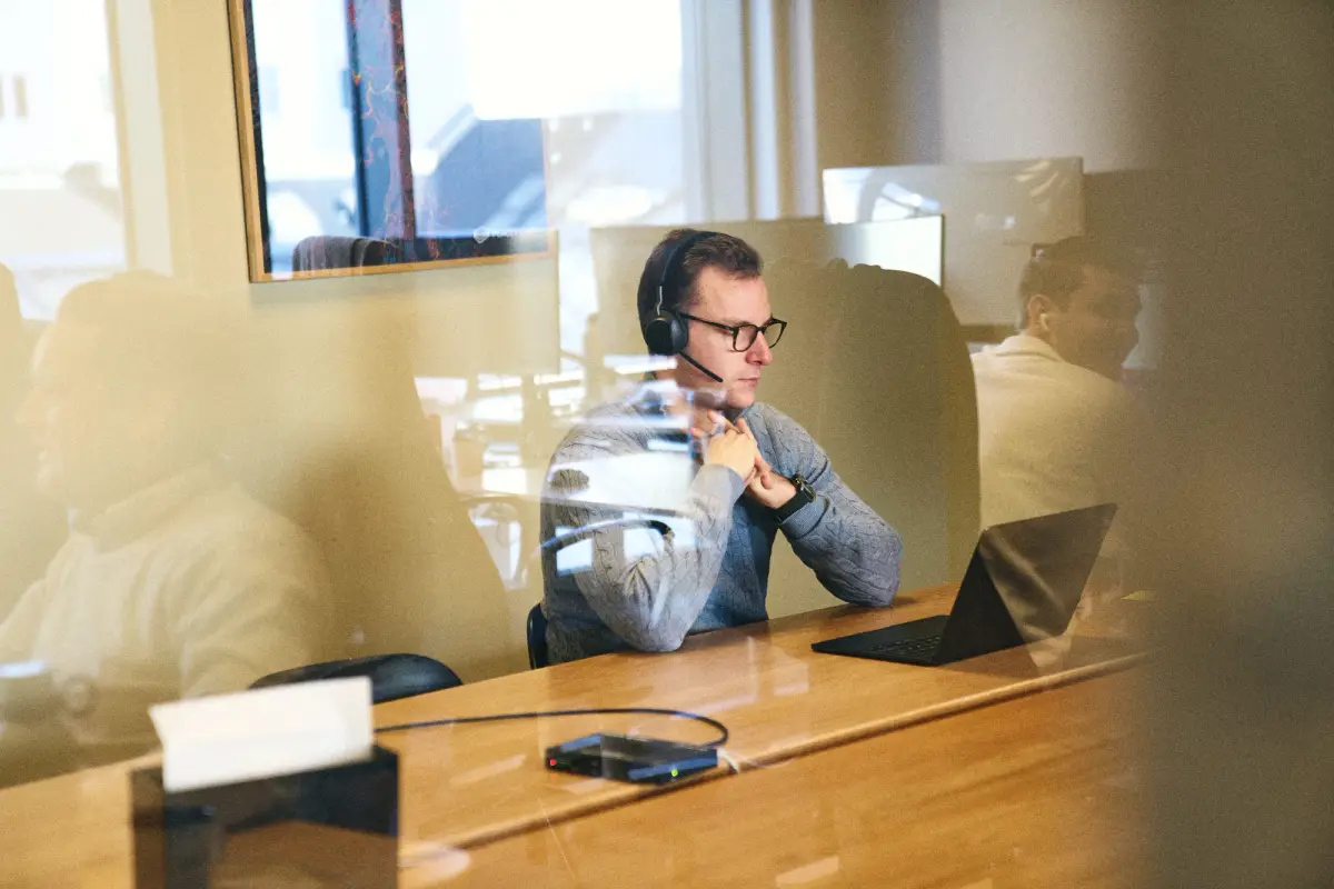 Colleague with a headset in a meeting room, photographed through the glass wall
