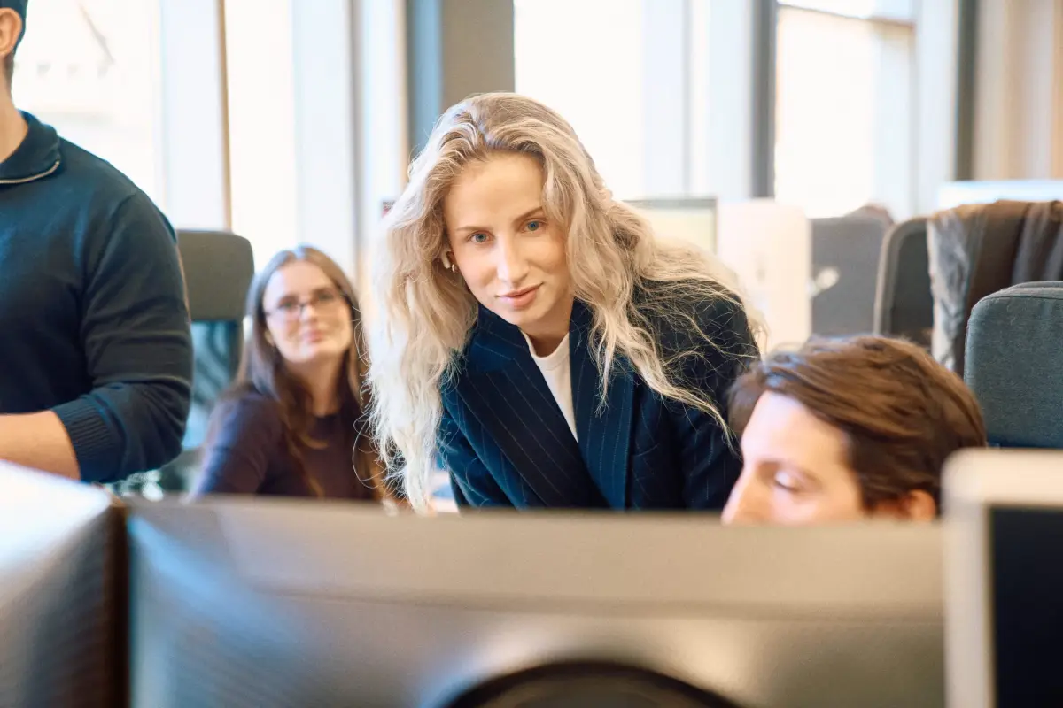 Colleagues gathered around a screen in the open-plan office